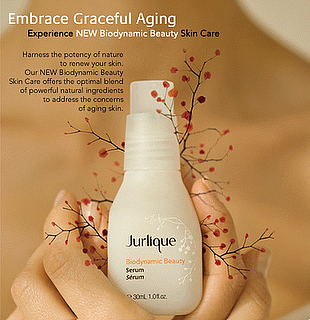 picture of Jurlique Serum in a caucasion hand with a berry branch and words that say embrace graceful aging, experience new biodynamic skin care, harness the potency of nature to renew your skin, our new biodynamic skin care offers the optimal blend of powerful of natural ingredients to address the concerns of aging