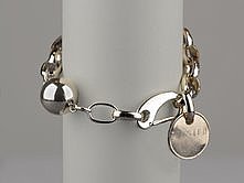 picture of Twisted Silver bracelet with chain links and a charm that says twisted on a gray background