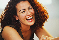 picture of dark and curly haired woman laughing with her mouth open