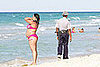 People enjoy the beach while a policeman patrols 